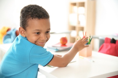 Cute little child sitting at desk in classroom. Elementary school