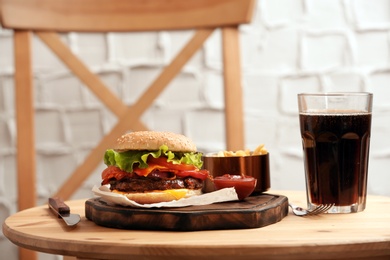 Photo of Burger, soda drink and french fries on table indoors, space for text