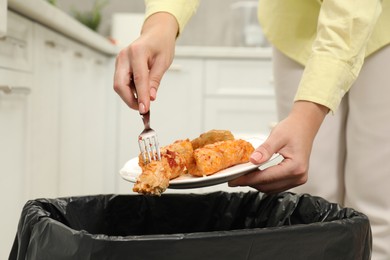 Photo of Woman throwing cabbage rolls into bin indoors, closeup