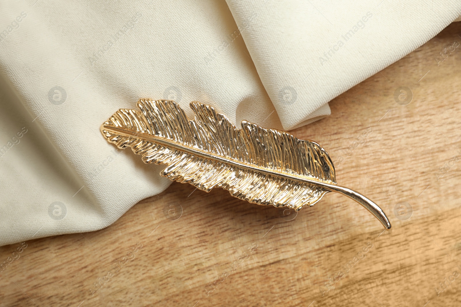 Photo of Stylish hair clip and fabric on wooden table, top view