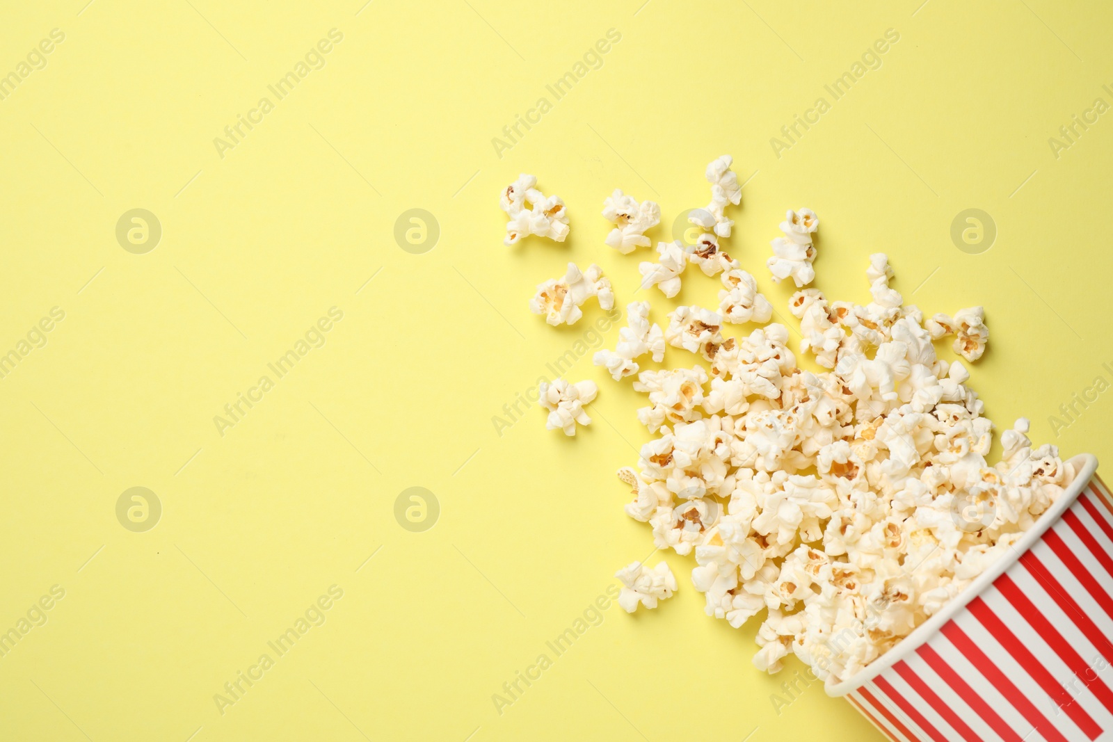 Photo of Delicious popcorn on yellow background, top view. Space for text