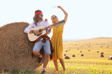 Photo of Beautiful hippie woman listening to her friend playing guitar in field, space for text