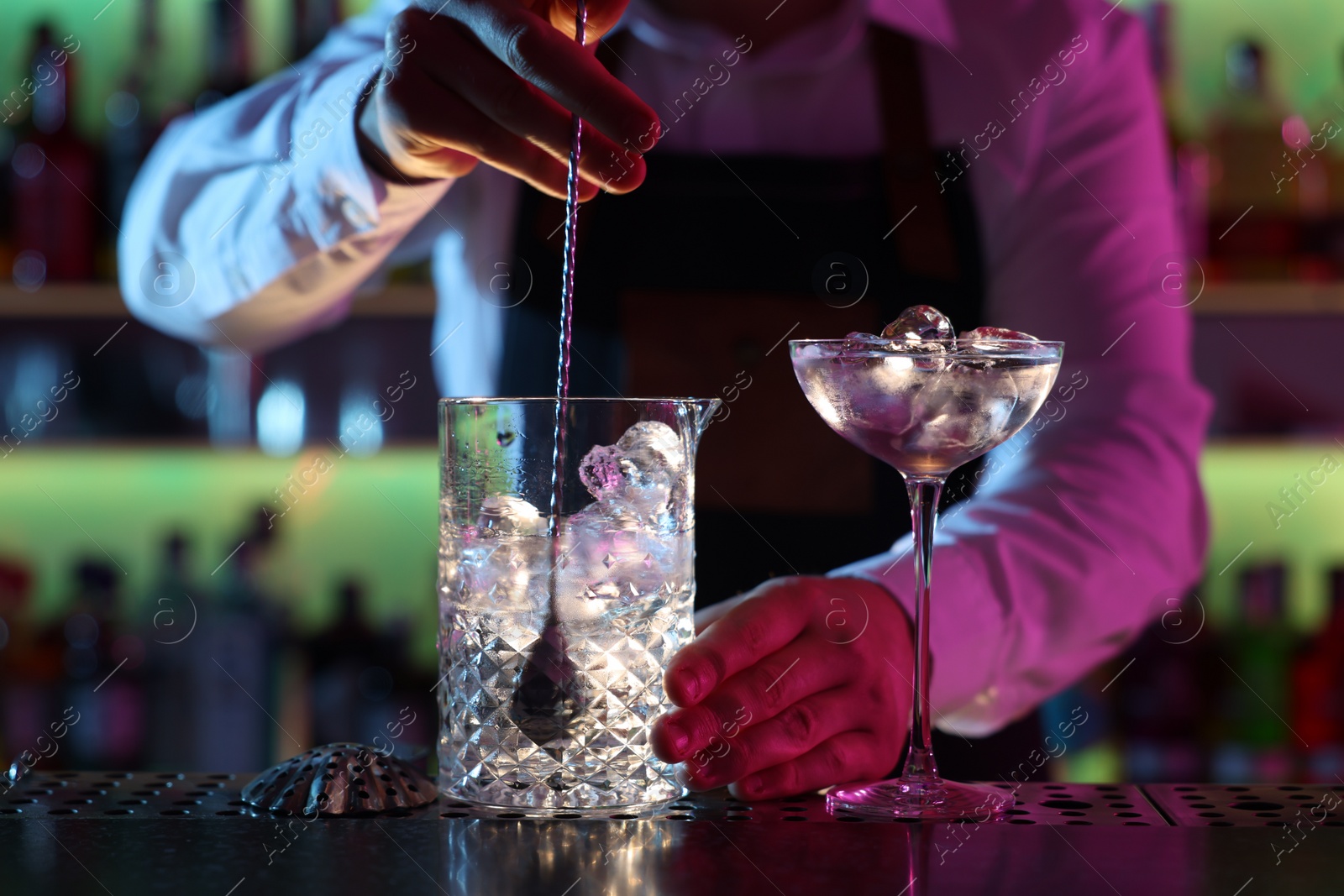 Photo of Bartender making fresh alcoholic cocktail at counter in bar, closeup