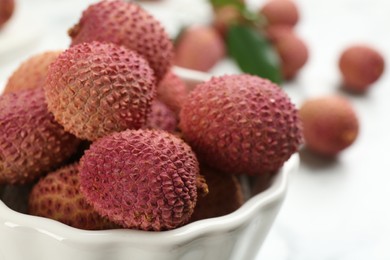Photo of Fresh ripe lychee fruits in ceramic bowl on table, closeup
