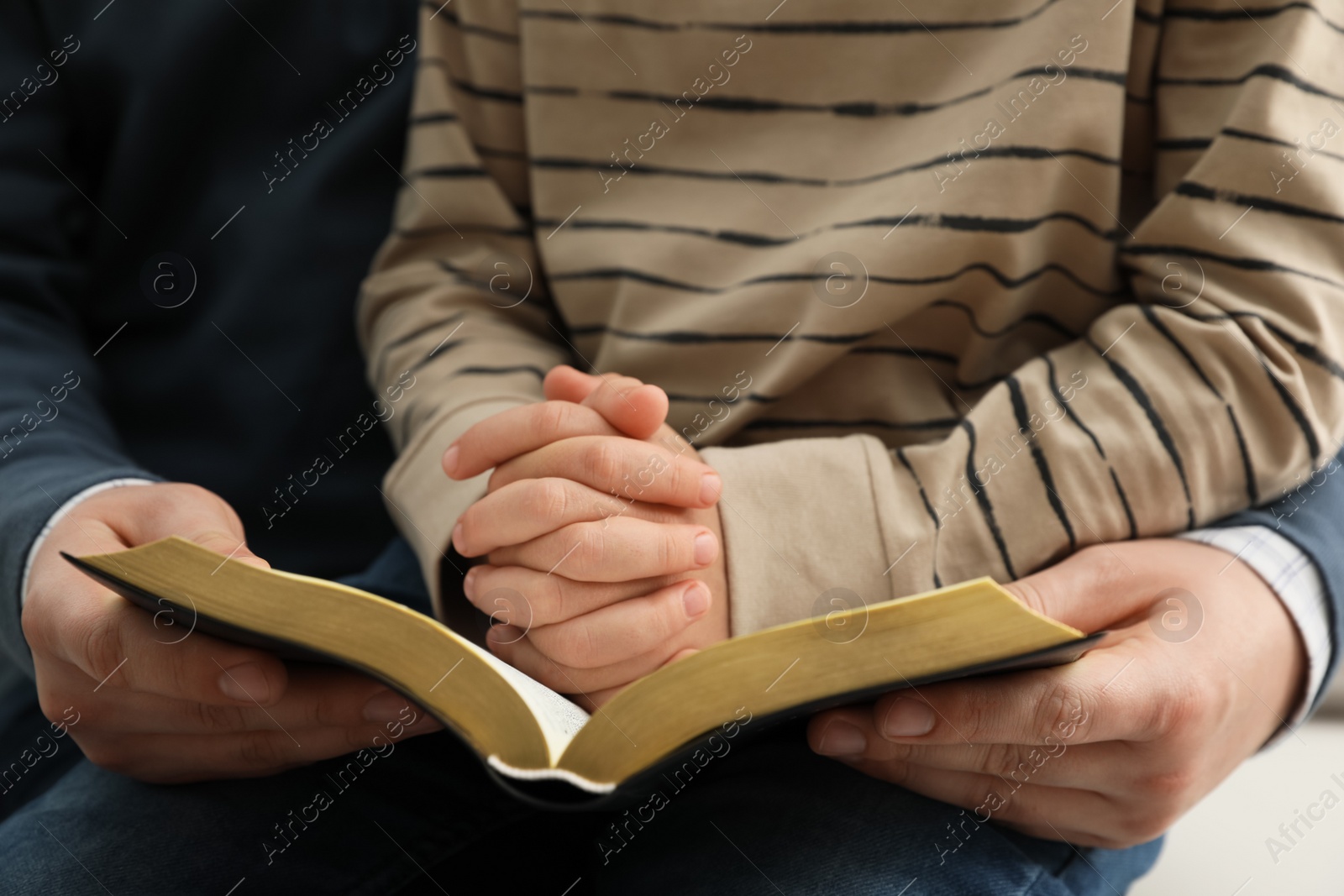 Photo of Boy and his godparent reading Bible together, closeup