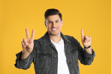 Photo of Man showing number three with his hands on yellow background