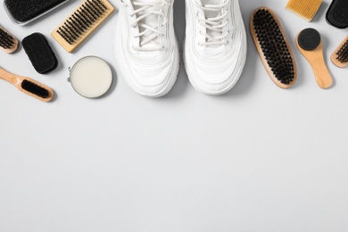 Flat lay composition with stylish footwear and shoe care accessories on white background, space for text