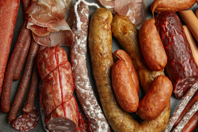 Photo of Different types of sausages on grey background, flat lay