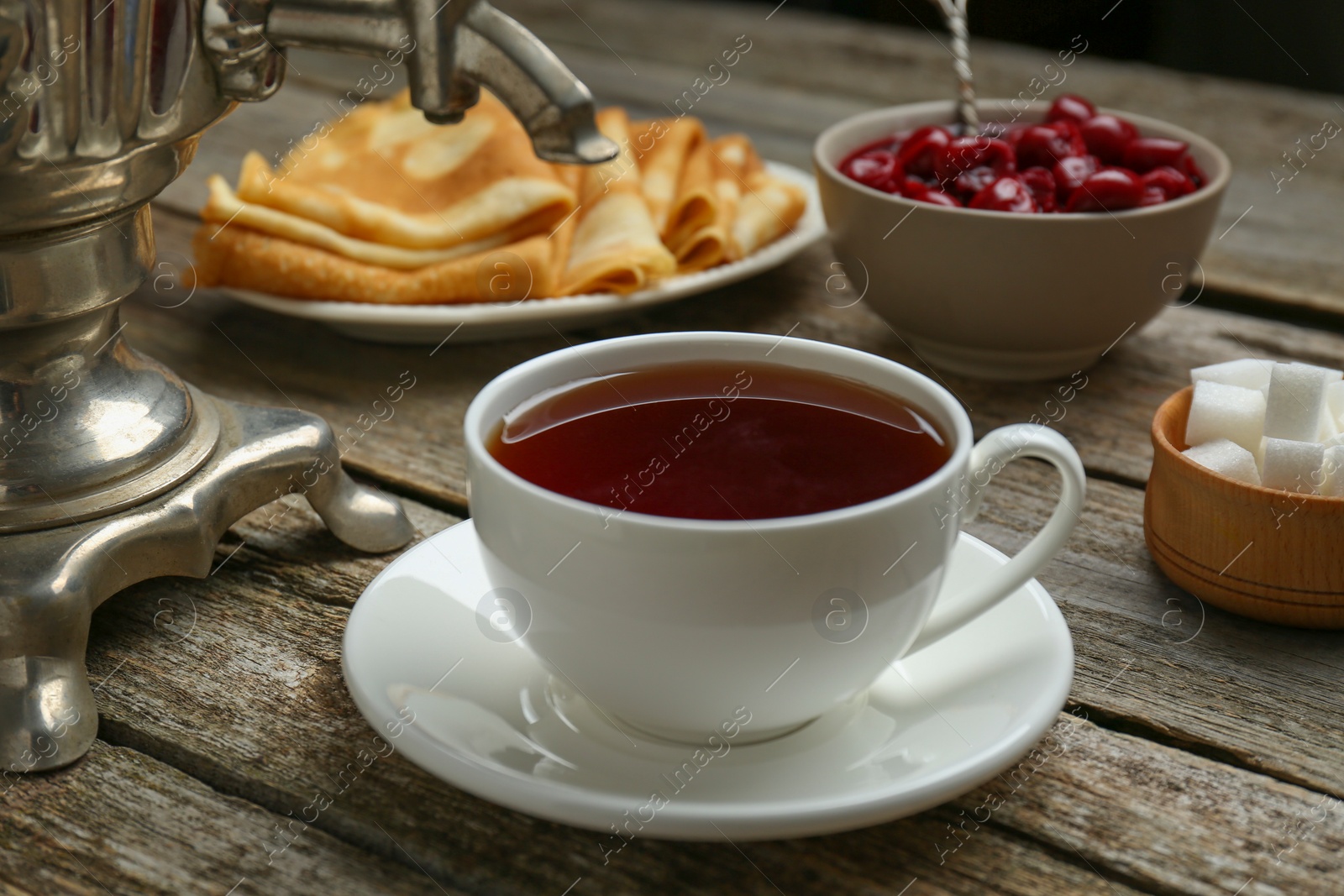 Photo of Metal samovar with cup of tea and treats on wooden table