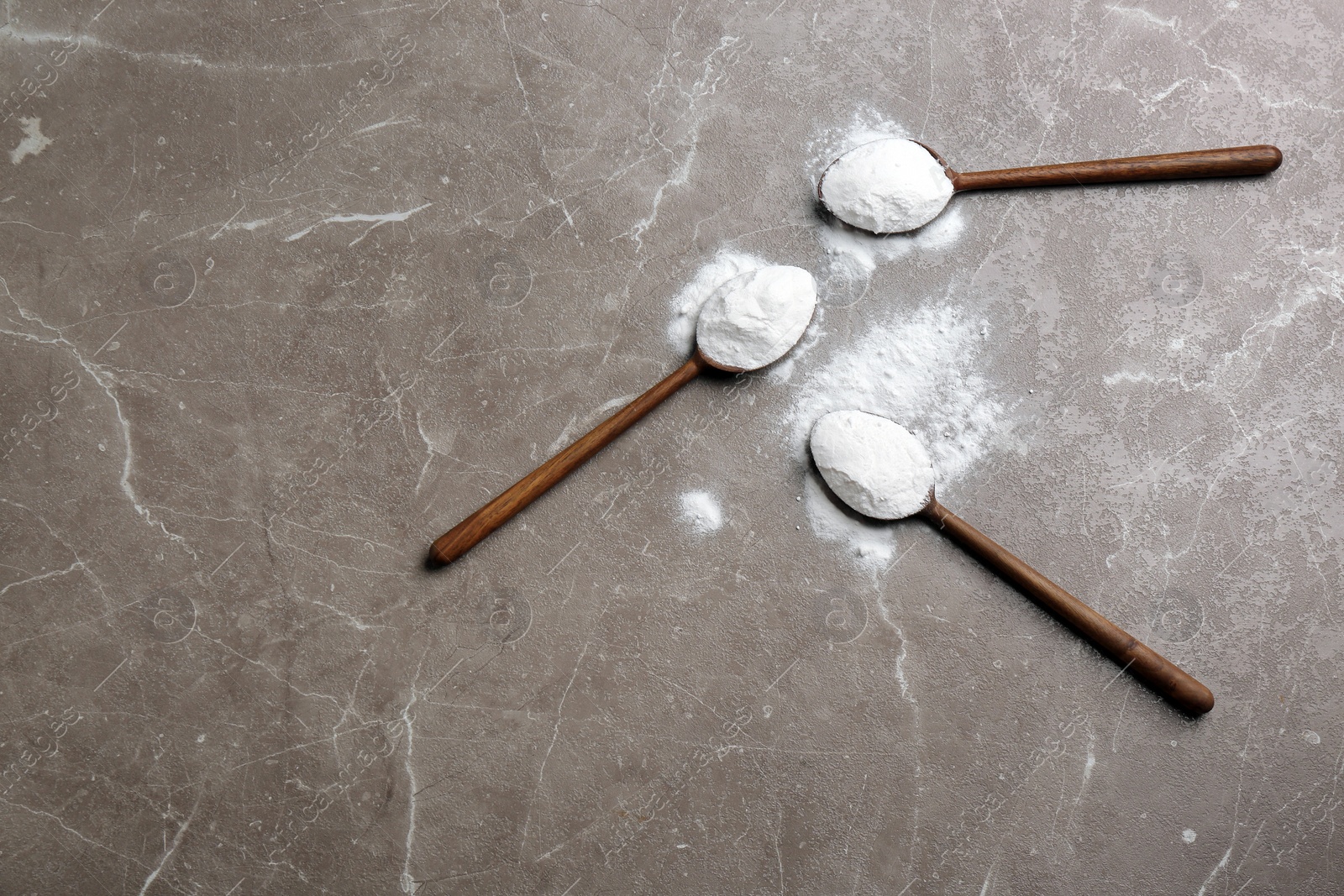 Photo of Spoons with baking soda on grey background, top view