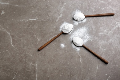 Spoons with baking soda on grey background, top view