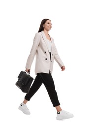 Beautiful businesswoman in suit with briefcase walking on white background