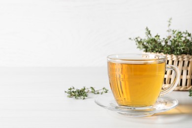 Photo of Aromatic herbal tea with thyme on white wooden table, space for text