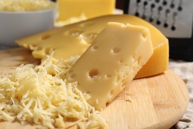 Photo of Grated and cut cheese on wooden board, closeup