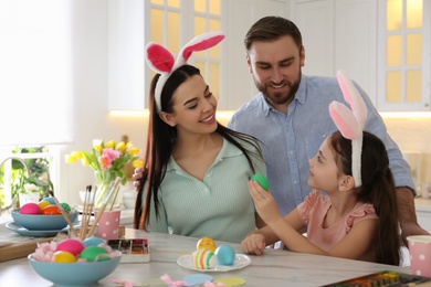 Happy family painting Easter eggs at table in kitchen