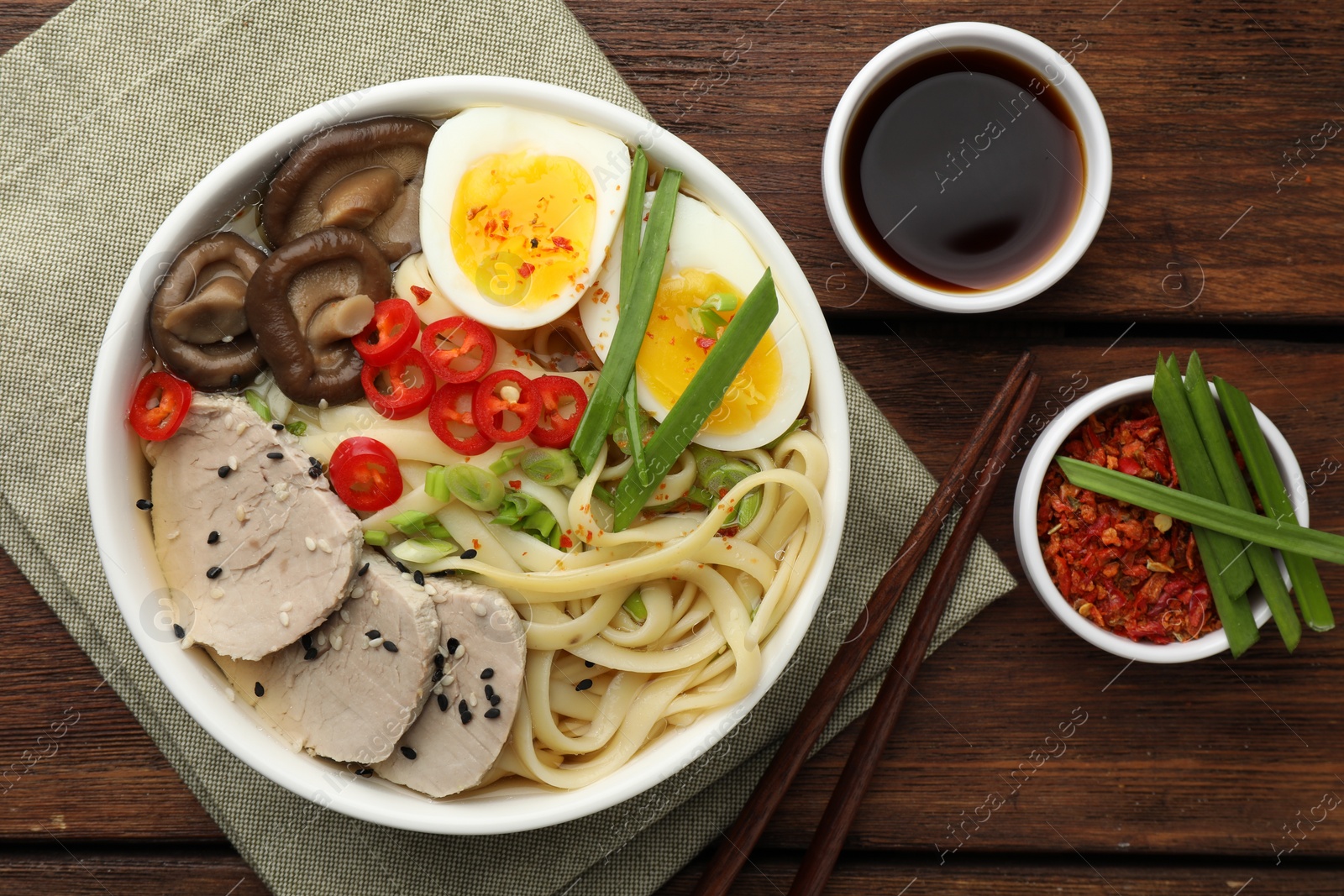 Photo of Delicious ramen with meat in bowl served on wooden table, flat lay. Noodle soup