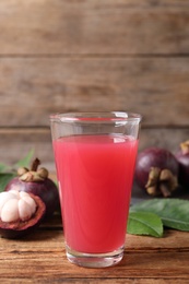 Photo of Delicious fresh mangosteen juice in glass on wooden table