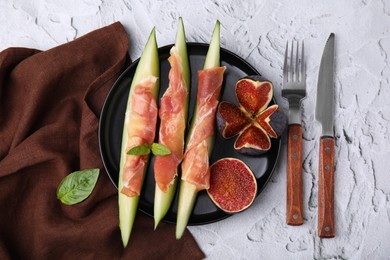 Photo of Tasty melon, jamon and figs served on white textured table, flat lay