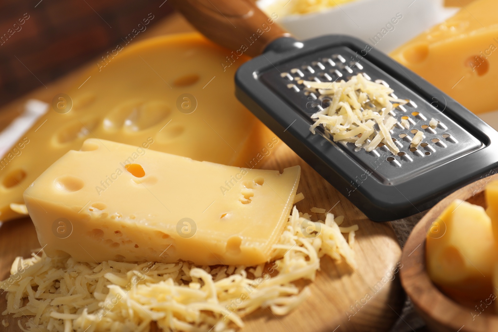 Photo of Grated, cut cheese and grater on table, closeup