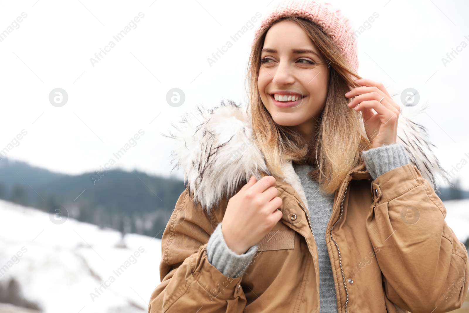 Photo of Young woman in warm clothes near snowy hill, space for text. Winter vacation