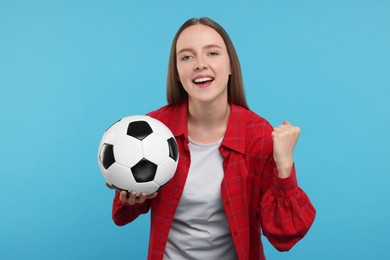 Emotional sports fan with ball on light blue background