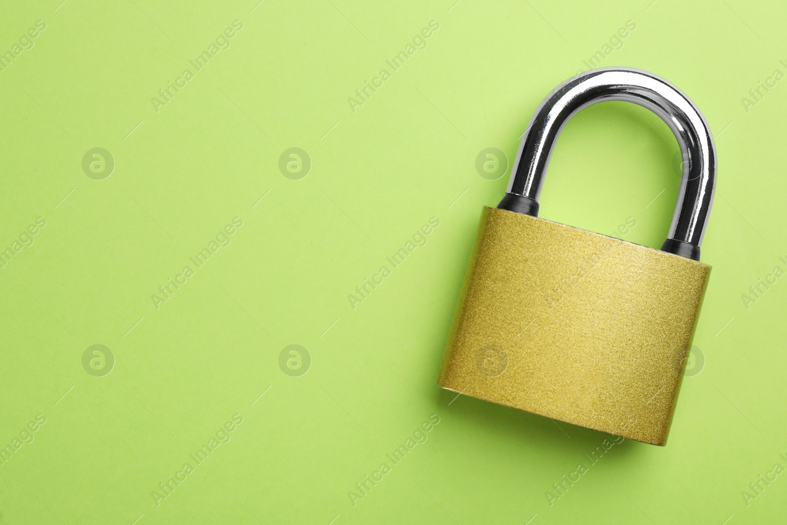 Photo of Modern padlock on green background, top view. Space for text
