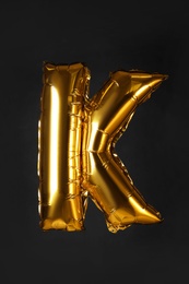 Photo of Golden letter K balloon on black background