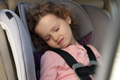 Photo of Cute little girl sleeping in child safety seat inside car