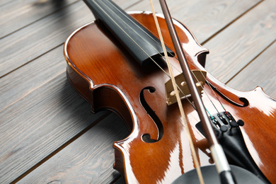 Photo of Classic violin and bow on wooden background, closeup