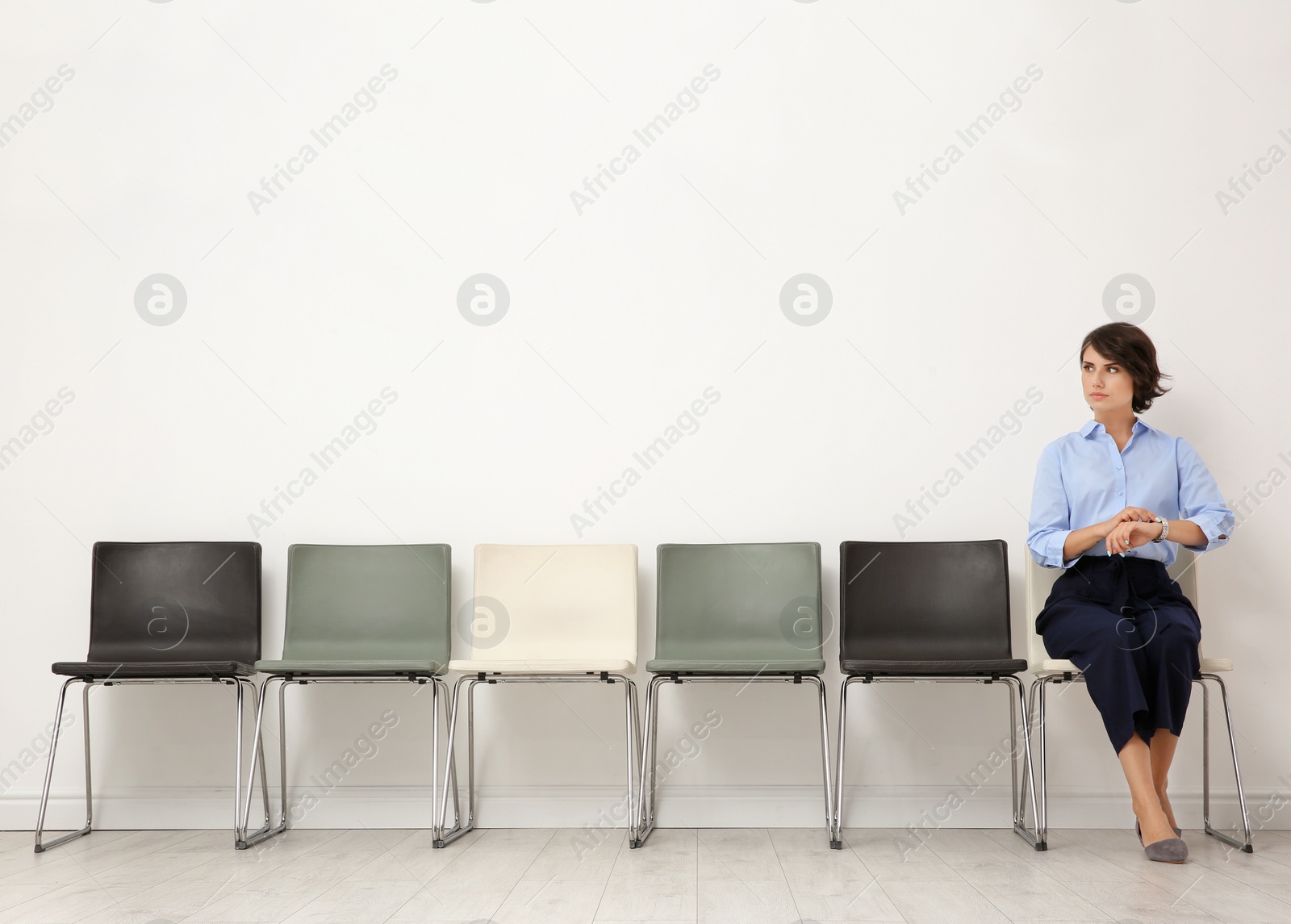 Photo of Young woman sitting on chair and waiting for job interview