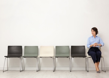 Young woman sitting on chair and waiting for job interview