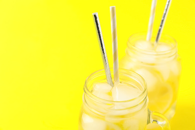 Photo of Closeup view of natural lemonade on yellow background, space for text. Summer refreshing drink