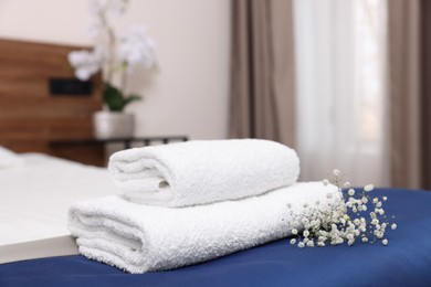 Photo of Stack of clean towels with flowers on bed in hotel room