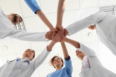 Photo of Team of medical workers holding hands together in hospital, bottom view. Unity concept