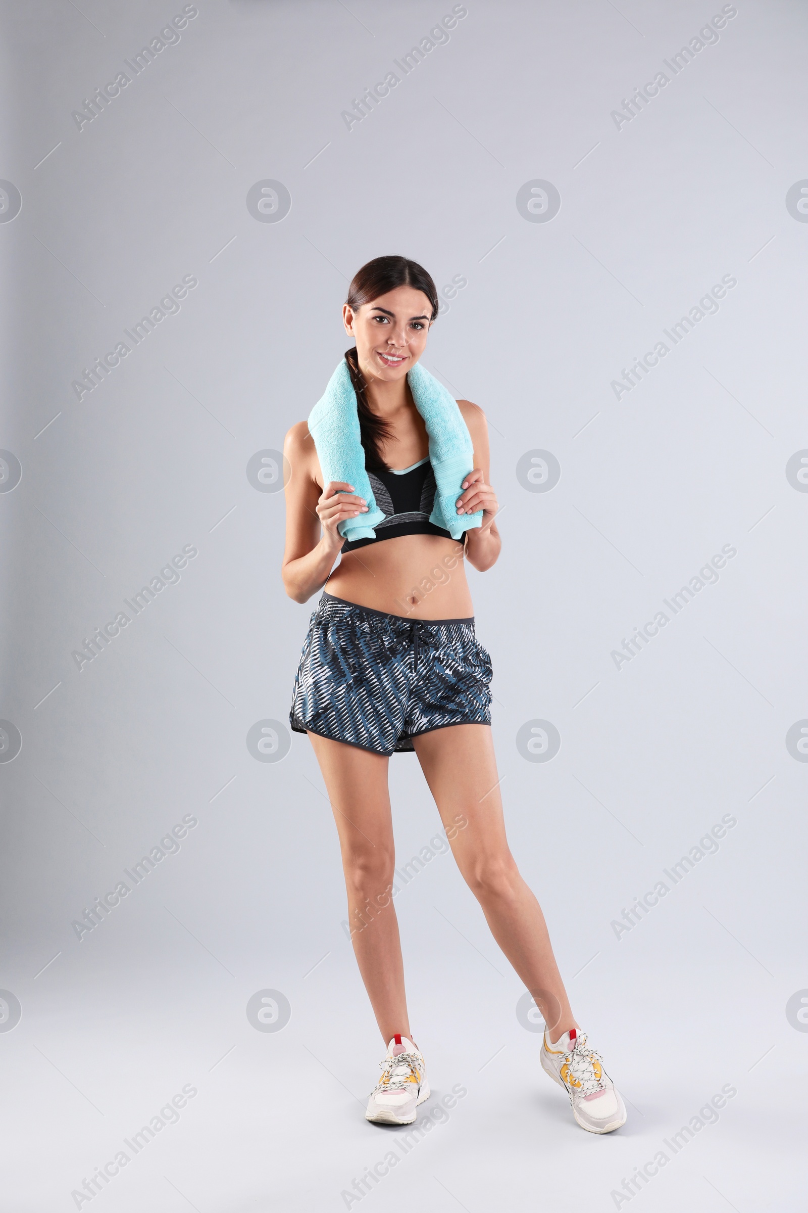 Photo of Beautiful young woman in sportswear with towel on white background