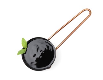 Balsamic glaze with basil leaves in metal small saucepan on white background, top view