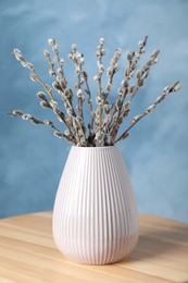 Photo of Beautiful bouquet of pussy willow branches in vase on wooden table