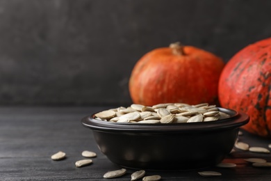 Photo of Full bowl of raw pumpkin seeds on wooden table