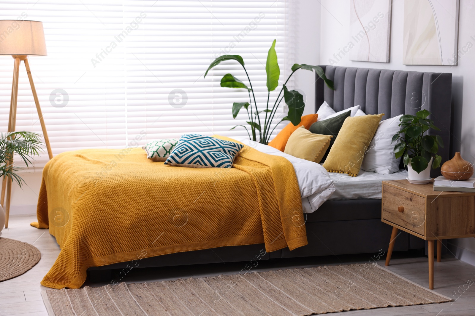 Photo of Bright plaid and colorful pillows on bed in stylish bedroom. Interior design