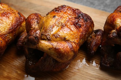 Delicious grilled whole chickens on wooden board, closeup