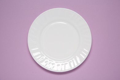 One white plate on violet background, top view