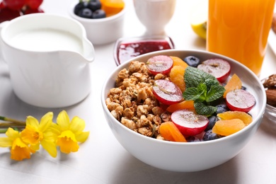 Photo of Delicious granola with fruits on white table, closeup
