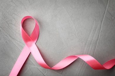 Pink ribbon on grey background, top view with space for text. Breast cancer awareness concept
