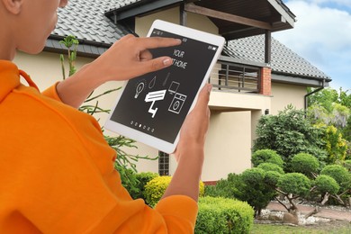 Image of Man using smart home control system via tablet near house outdoors, closeup