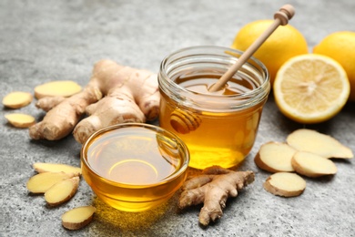 Photo of Honey, ginger and lemon on grey table. Natural cold remedies