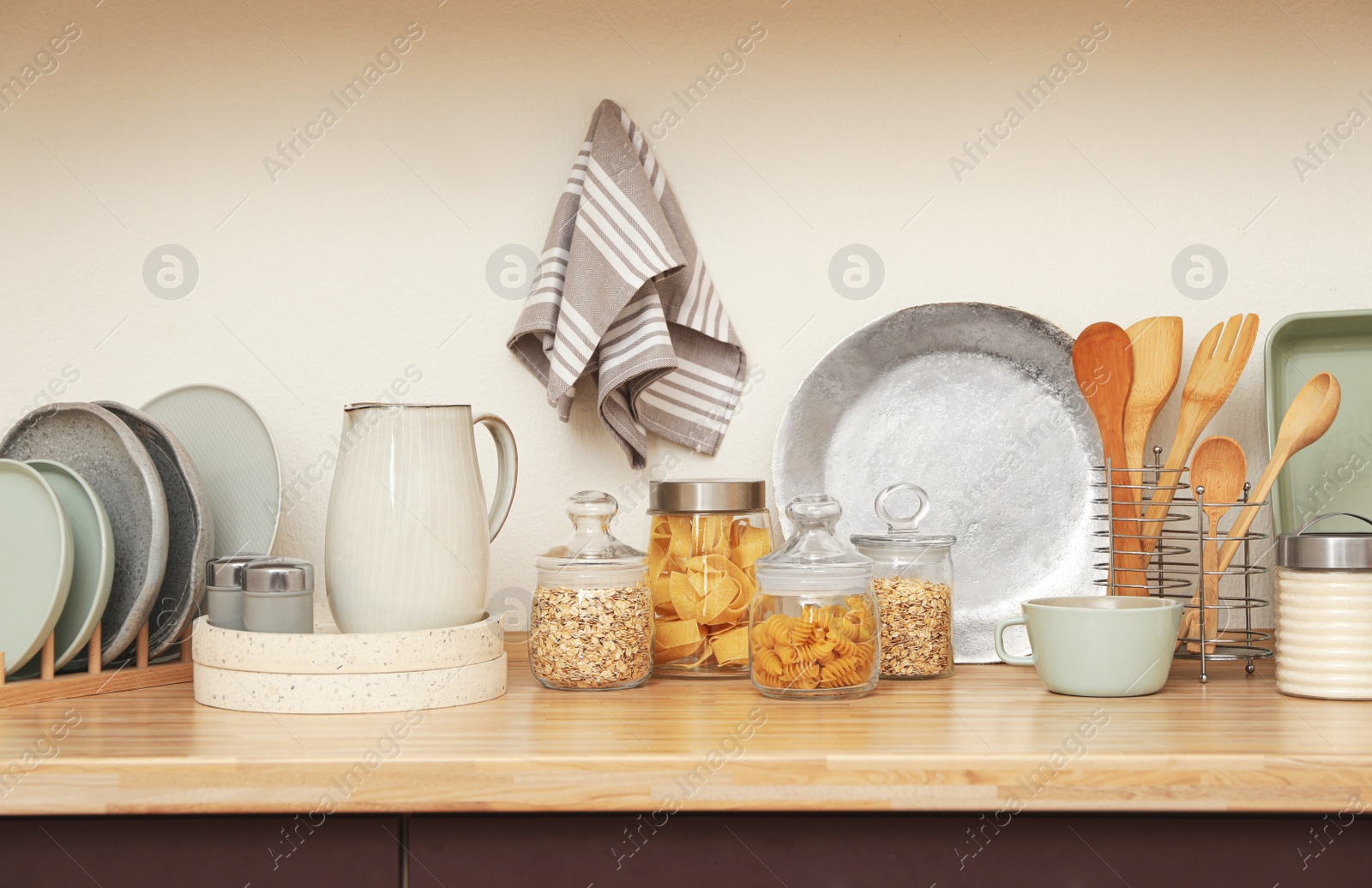 Photo of Wooden countertop with dishware and products near white wall. Kitchen interior idea