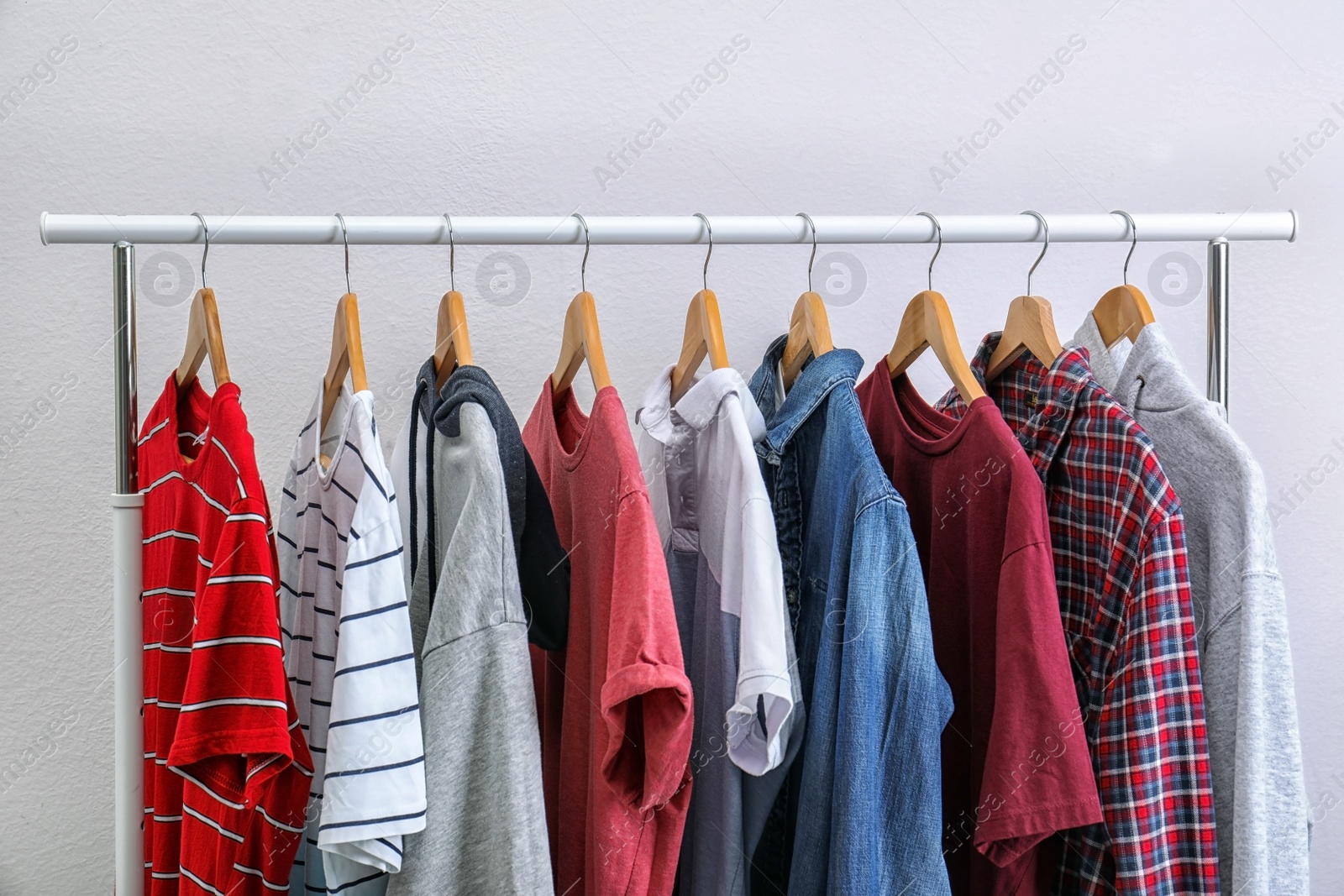 Photo of Stylish clothes hanging on wardrobe rack against light background