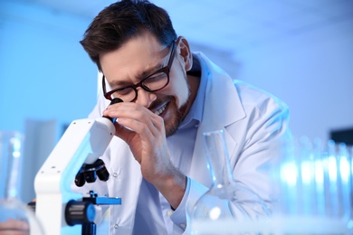 Male scientist using modern microscope in chemistry laboratory