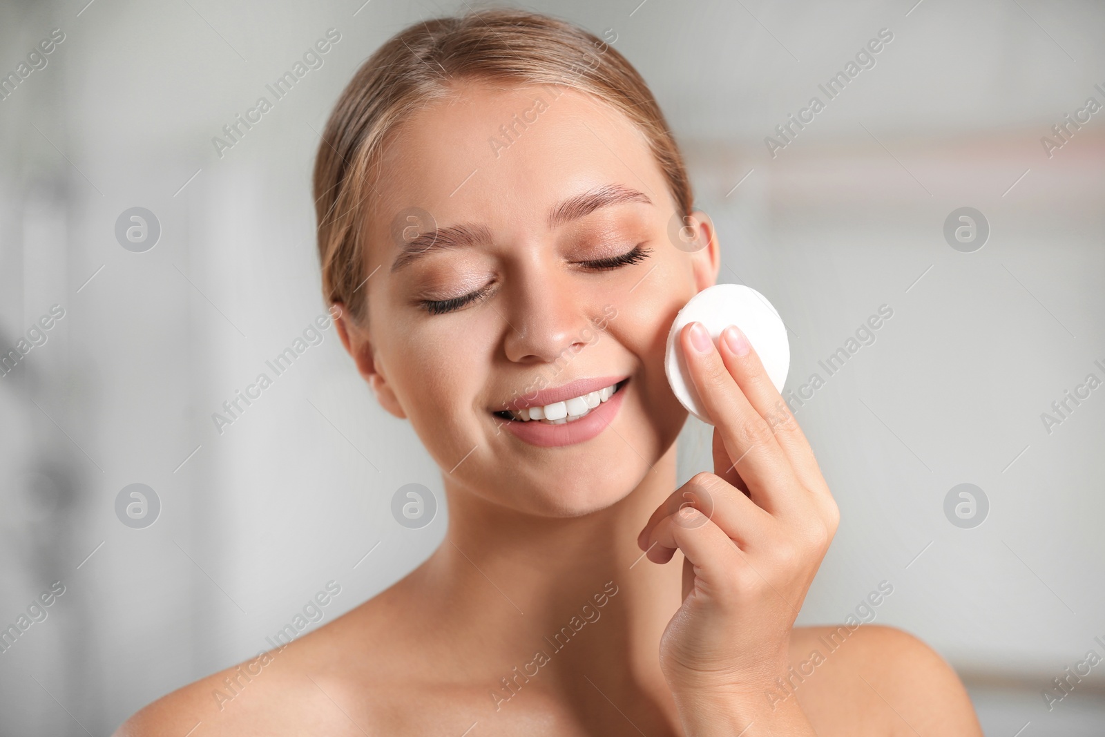 Photo of Beautiful young woman with cotton pad indoors