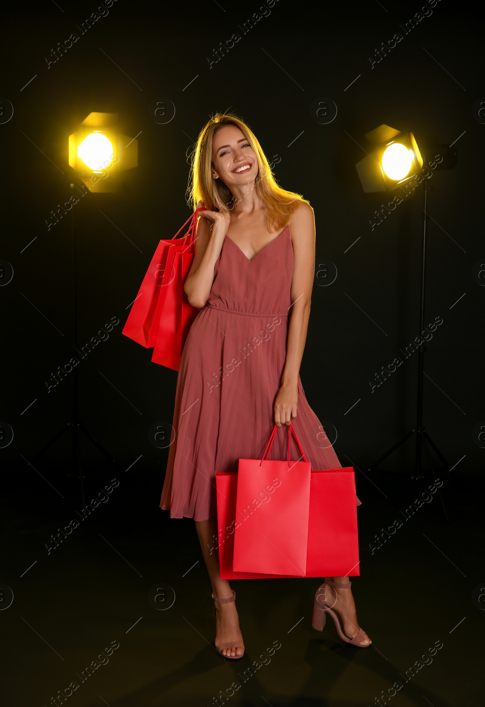 Photo of Happy young woman with shopping bags on dark background. Black Friday Sale